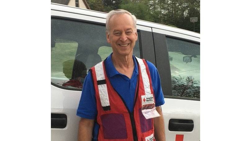 Gary Weinstein wearing a Red Cross vest and standing next to a Red Cross van.