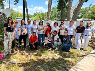 a group of people pose for a picture outside under the shade of palm trees.