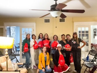 a group of people holding Red Cross bags pose for a picture indside a home.