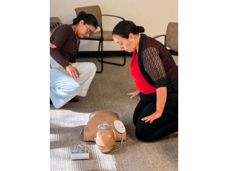 two people practice CPR on a manikin.