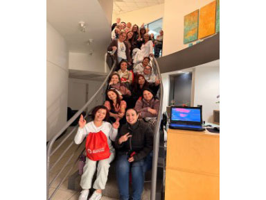 a group of people pose for a picture on a staircase inside an office building.