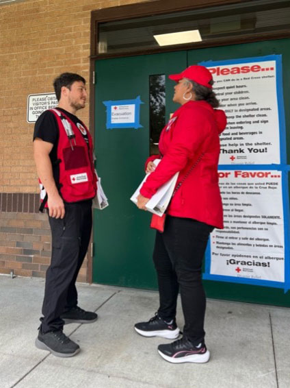 Red Cross volunteer, James Jones standing next to another volunteer outside a Red Cross shelter.