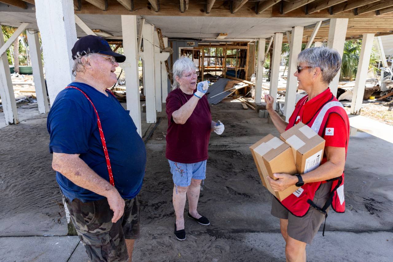 August 31, 2023. Horseshoe Beach, Florida.
Red Cross disaster responder, Holly Swiney, communicates in sign language with Horseshoe Beach, Florida, residents Jerry and Gracie McEver, underneath the couple s damaged home. Red Cross volunteers are delivering meal kits and supplies in hard-hit neighborhoods after Hurricane Idalia. As a result of the climate crisis, hurricanes are becoming more intense and more destructive with increased rainfall and higher storm surges.
Photo by Scott Dalton/American Red Cross