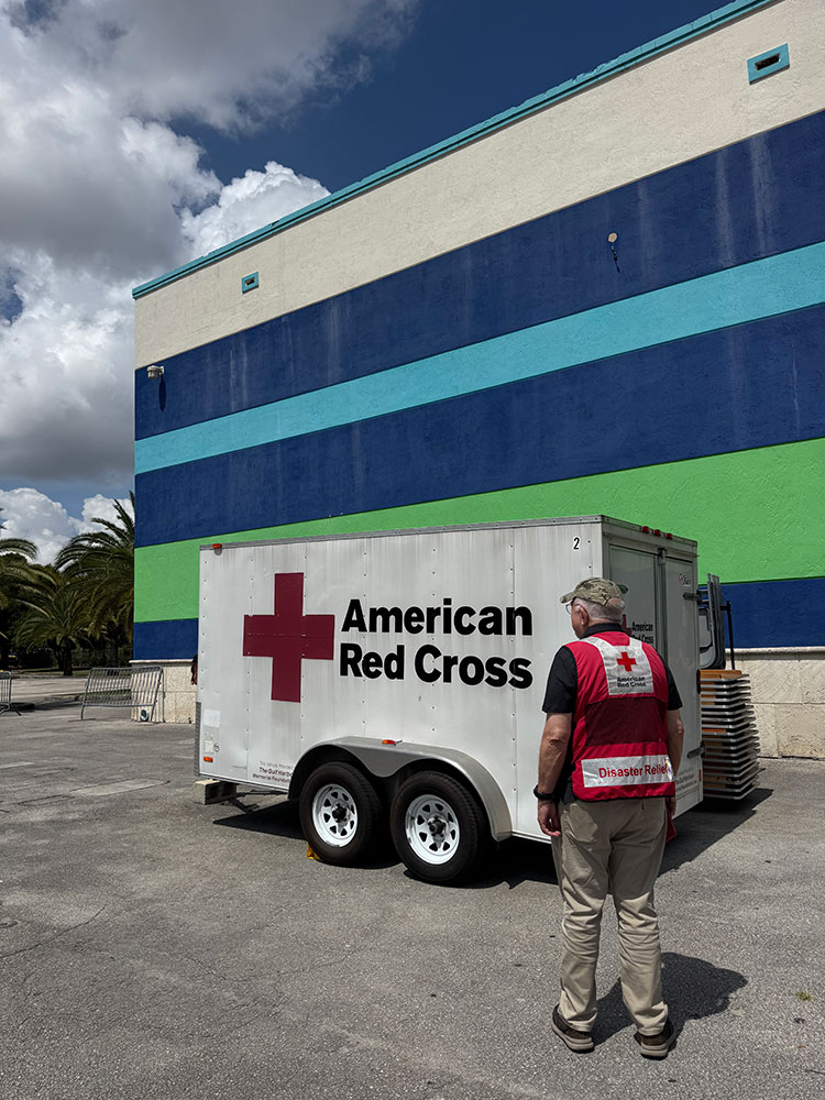 Red Cross volunteer standing next to a Red Cross trailer.