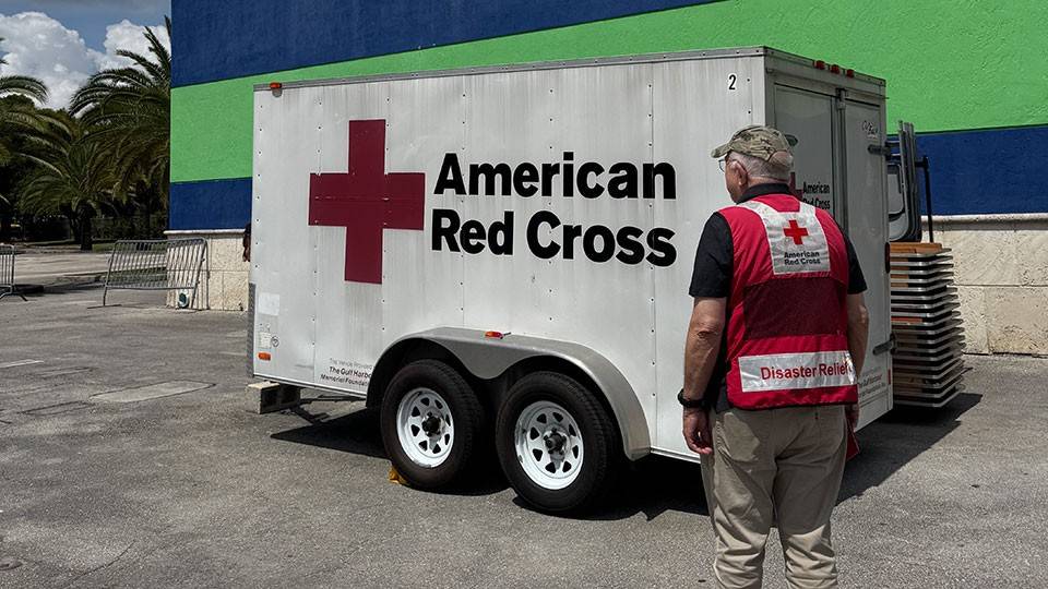 Red Cross volunteer standing next to a Red Cross trailer.