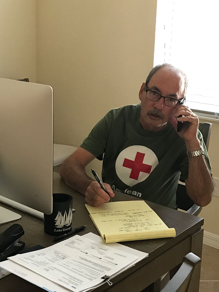 Red Cross volunteer, Mike Germain sitting at a desk and talking on a phone.