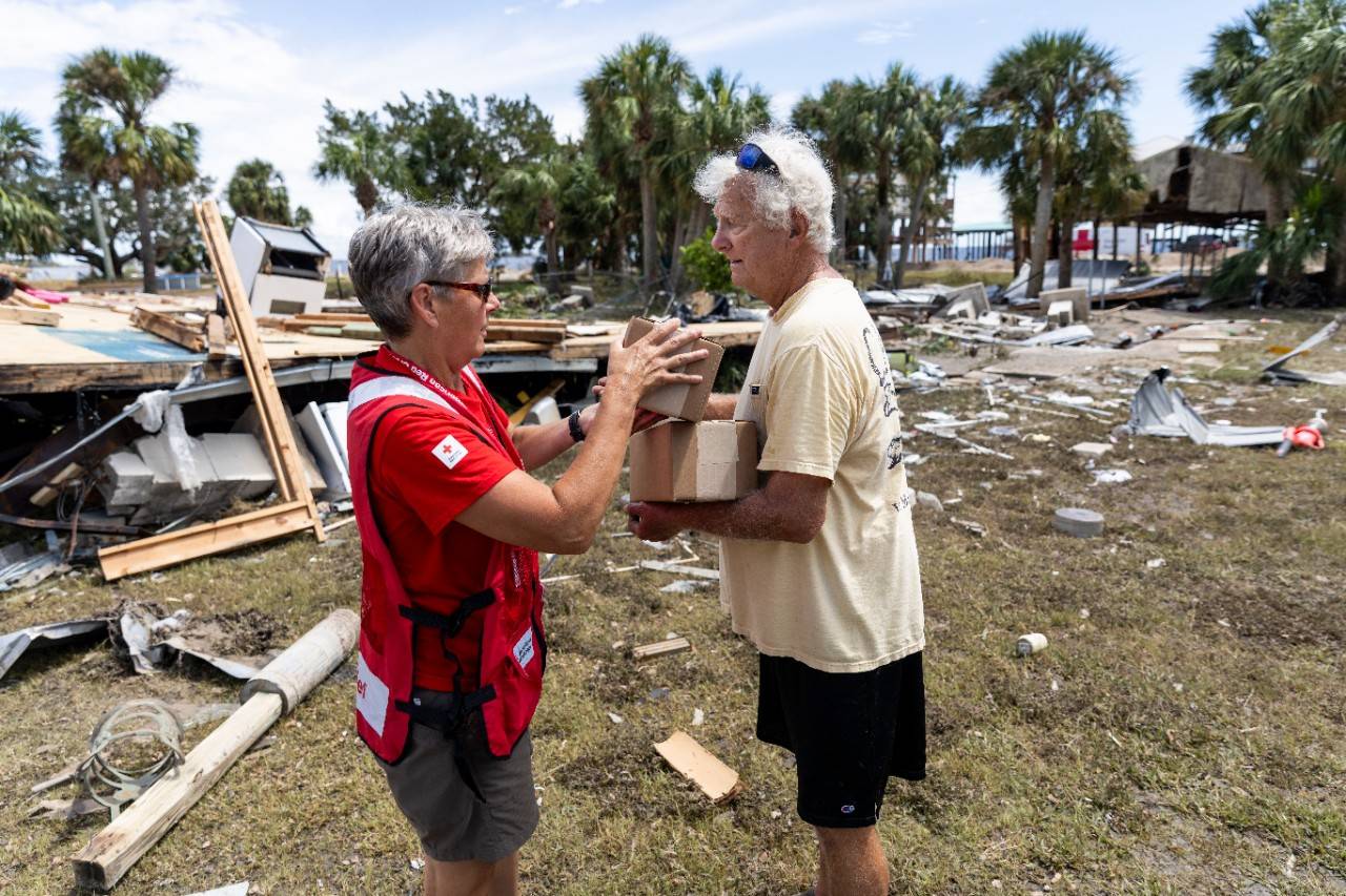 August 31, 2023. Horseshoe Beach, Florida.
Red Cross disaster responder, Holly Swiney, hands meal kits to Jerry Sapp for his family near his destroyed home in Horseshoe Beach, Florida. With their emergency response vehicle, Red Cross volunteers are delivering food and supplies in hard-hit neighborhoods after Hurricane Idalia. As a result of the climate crisis, hurricanes are becoming more intense and more destructive with increased rainfall and higher storm surges.
Photo by Scott Dalton/American Red Cross