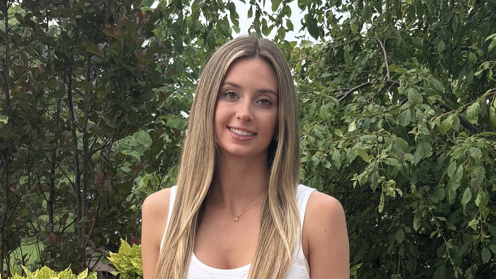 photo of a young woman standing in front of trees.