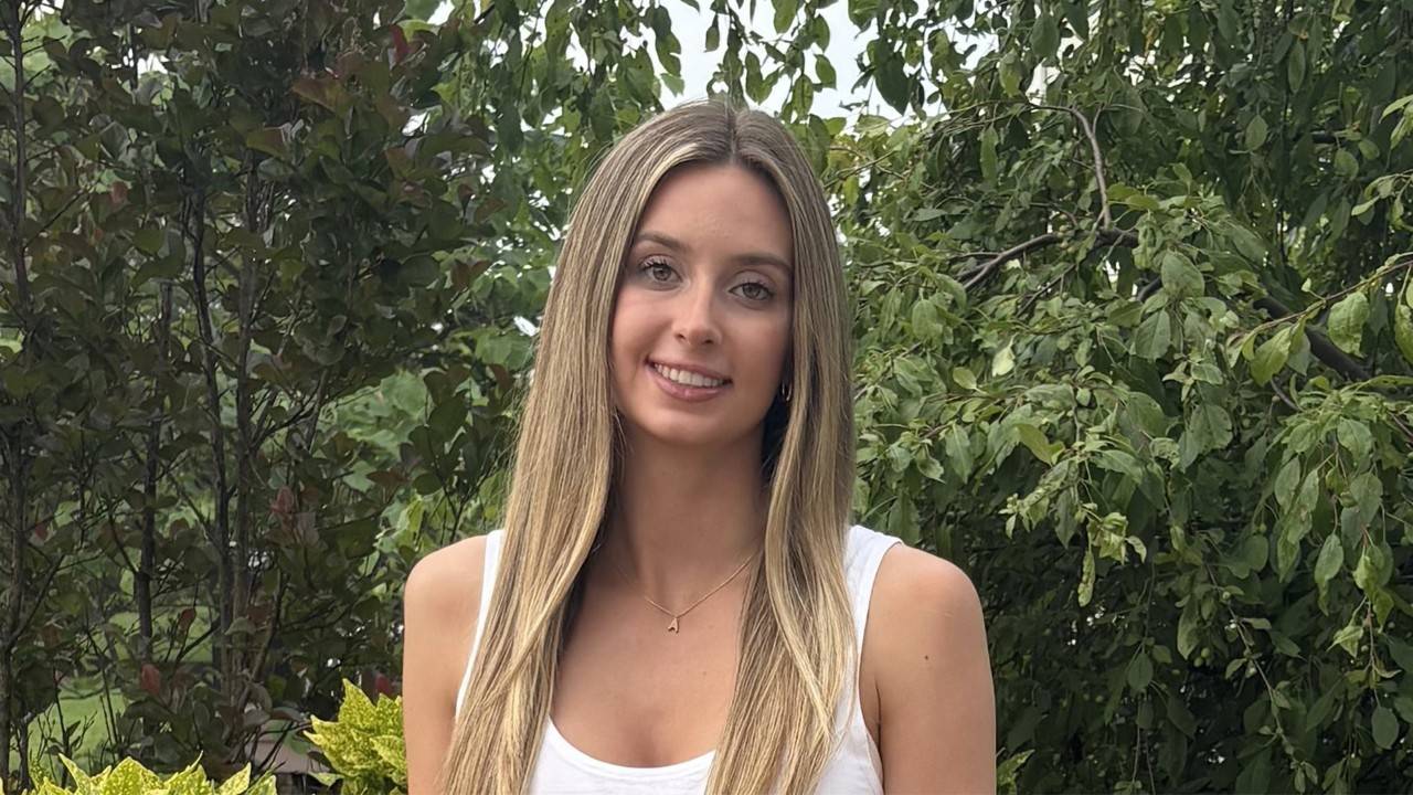 photo of a young woman standing in front of trees.