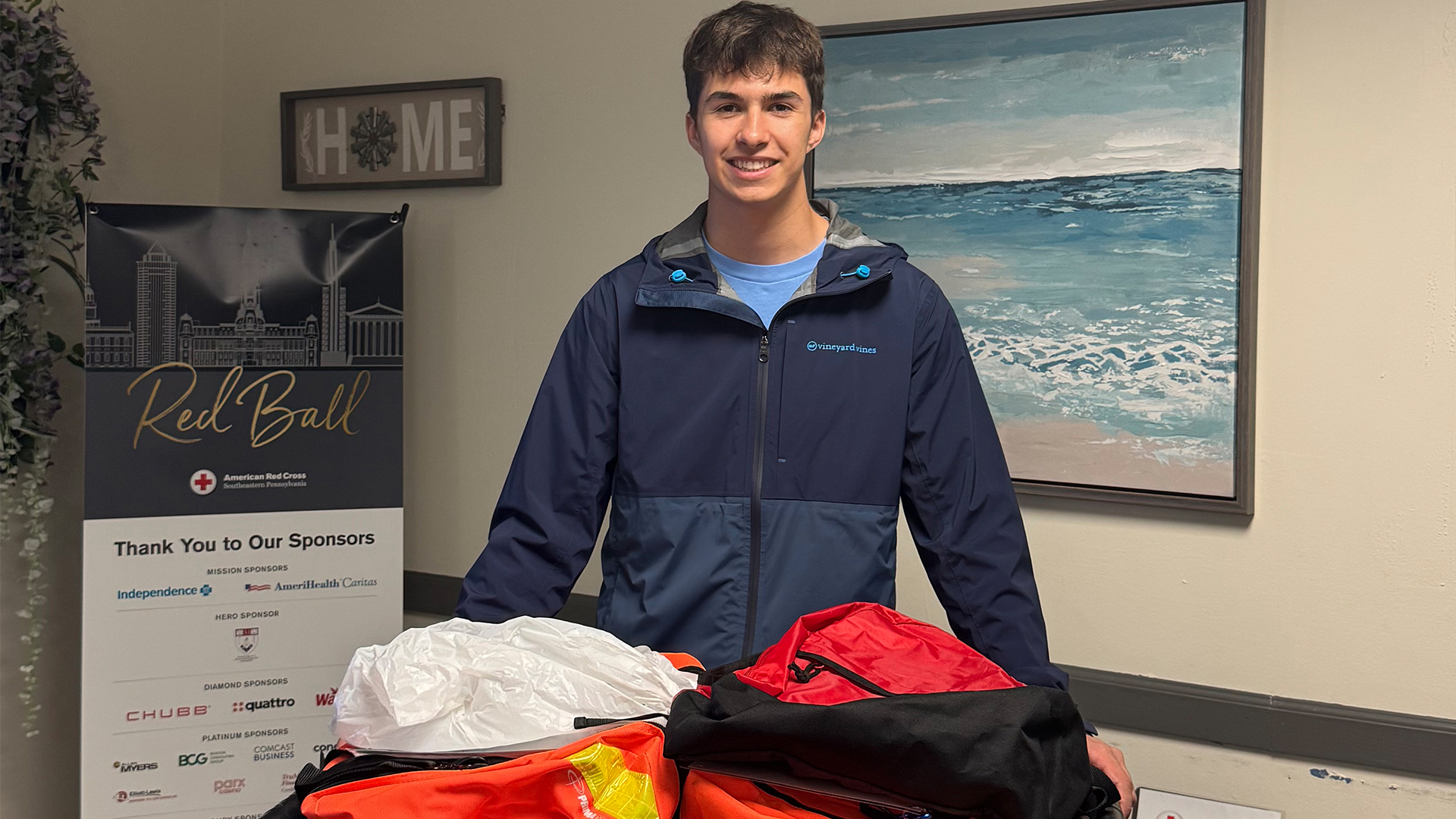 Ben Michel stands with several large orange go bags.
