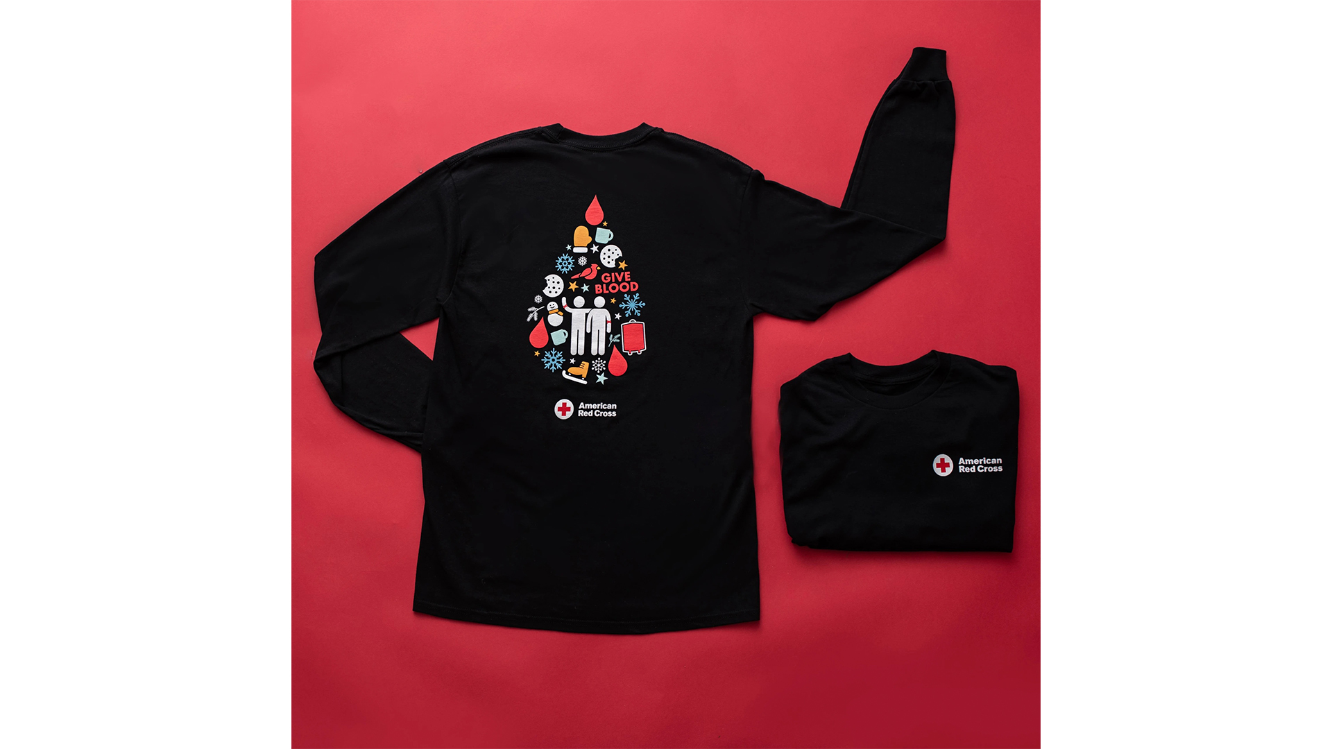 Photo of a long sleeved black T-shirt on a red background. The T-shirt features holiday symbols and blood drops together in a teardrop shape.