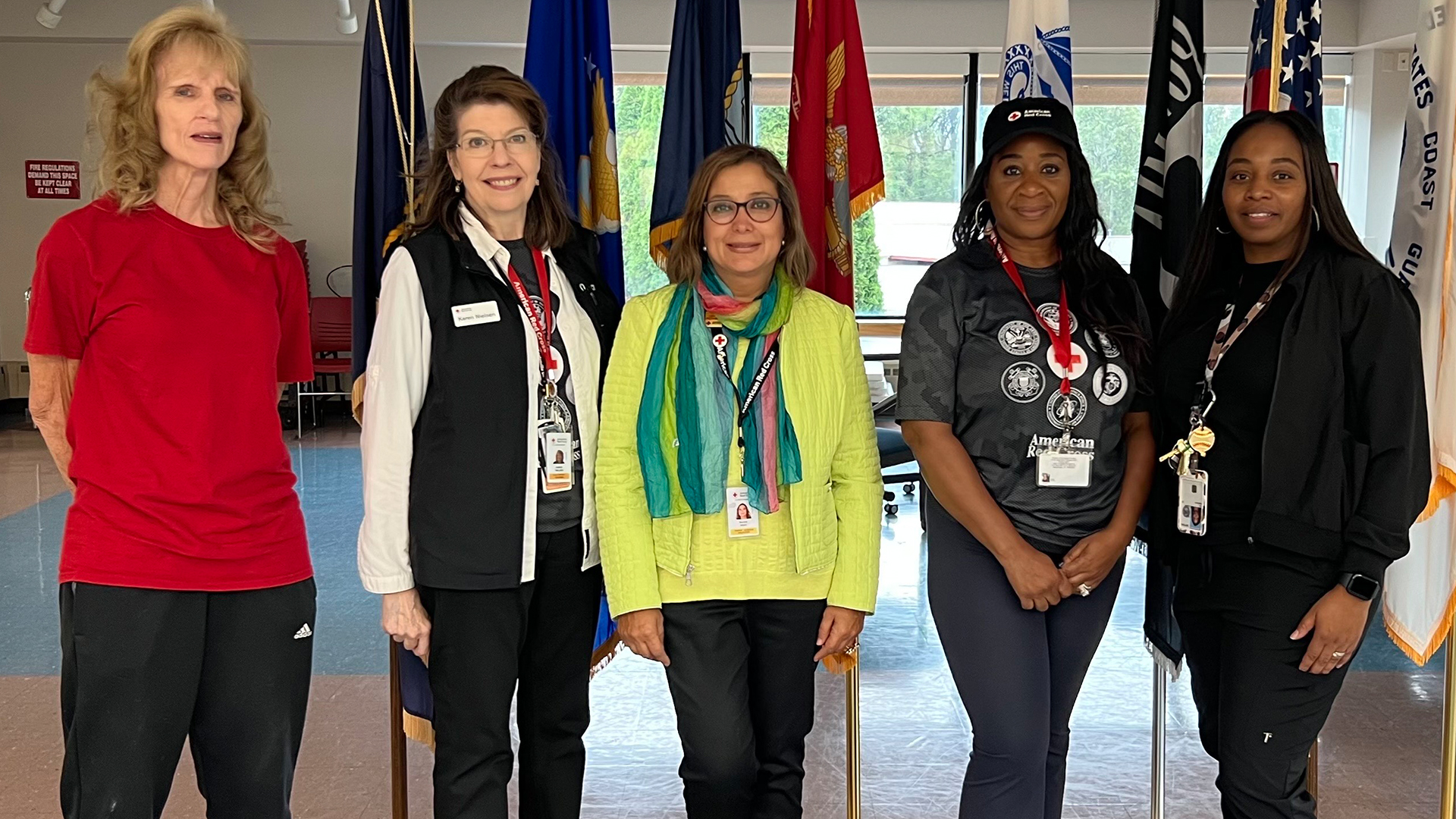 Five women standing in front of several flags.