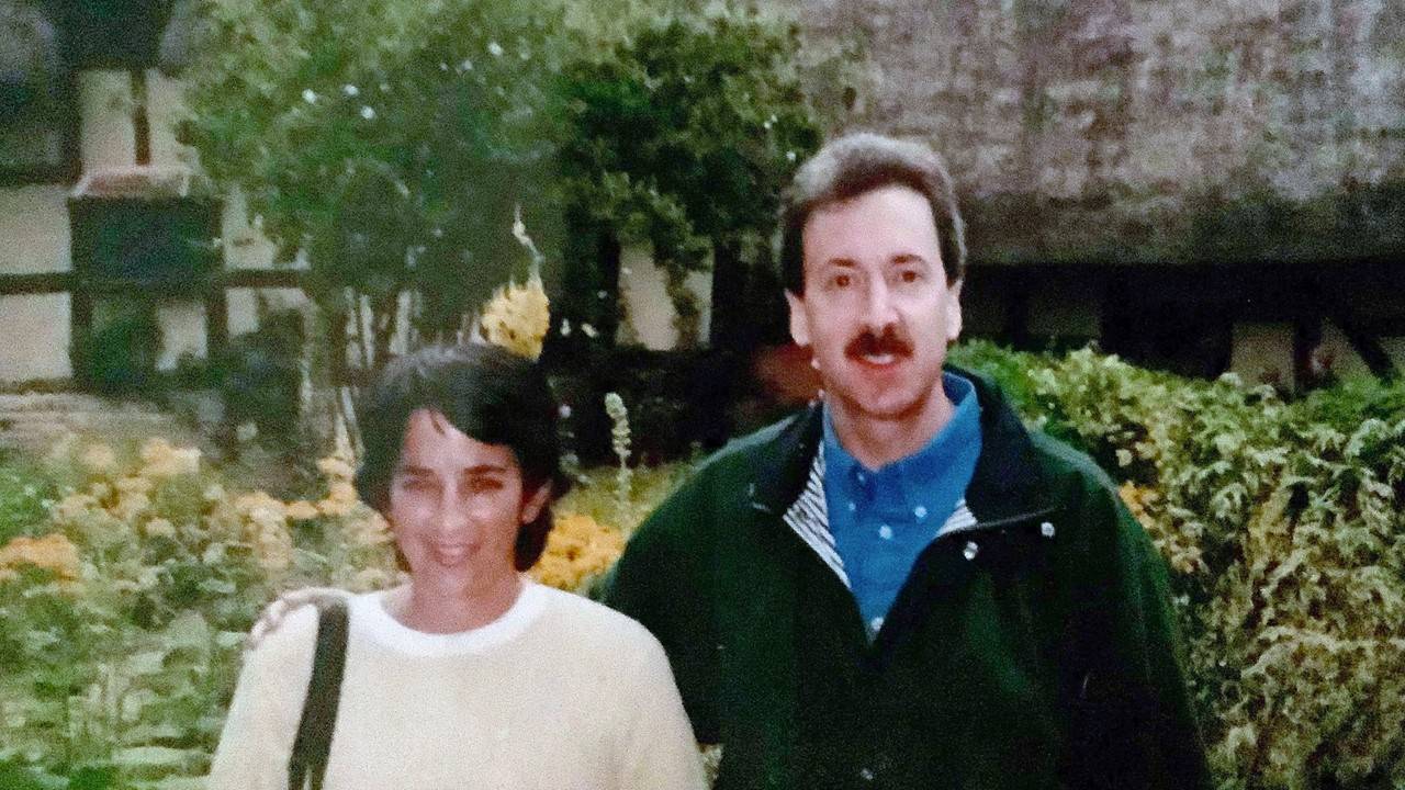 A white woman and man standing in front of trees.