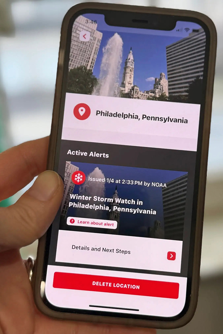 Hand holding a smartphone displaying the American Red Cross Emergency app showing active weather alerts, including a Winter Storm Watch, for Philadelphia, Pennsylvania.