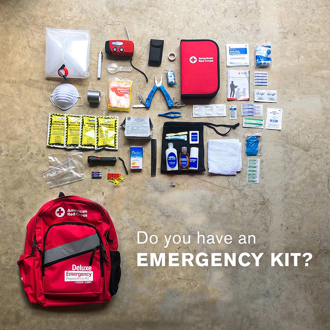 Top-down view of emergency kit supplies neatly arranged on a concrete floor next to a red American Red Cross backpack, with text reading "Do you have an EMERGENCY KIT?"