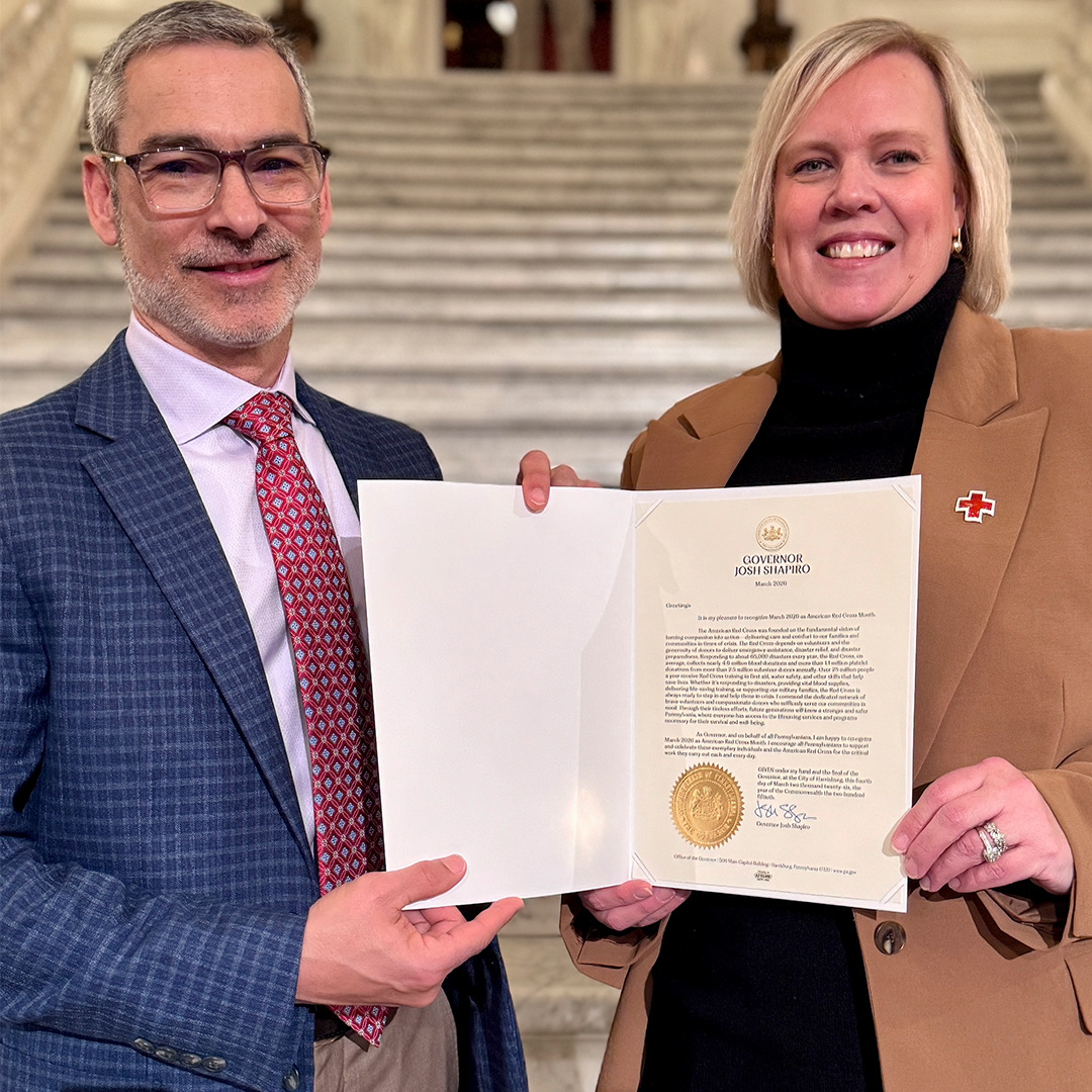 Red Cross Greater Pennsylvania Region CEO Jorge Martinez and Southeastern Pennsylvania CEO Jennifer Graham hold a proclamation from Governor Josh Shapiro recognizing March as Red Cross Month
