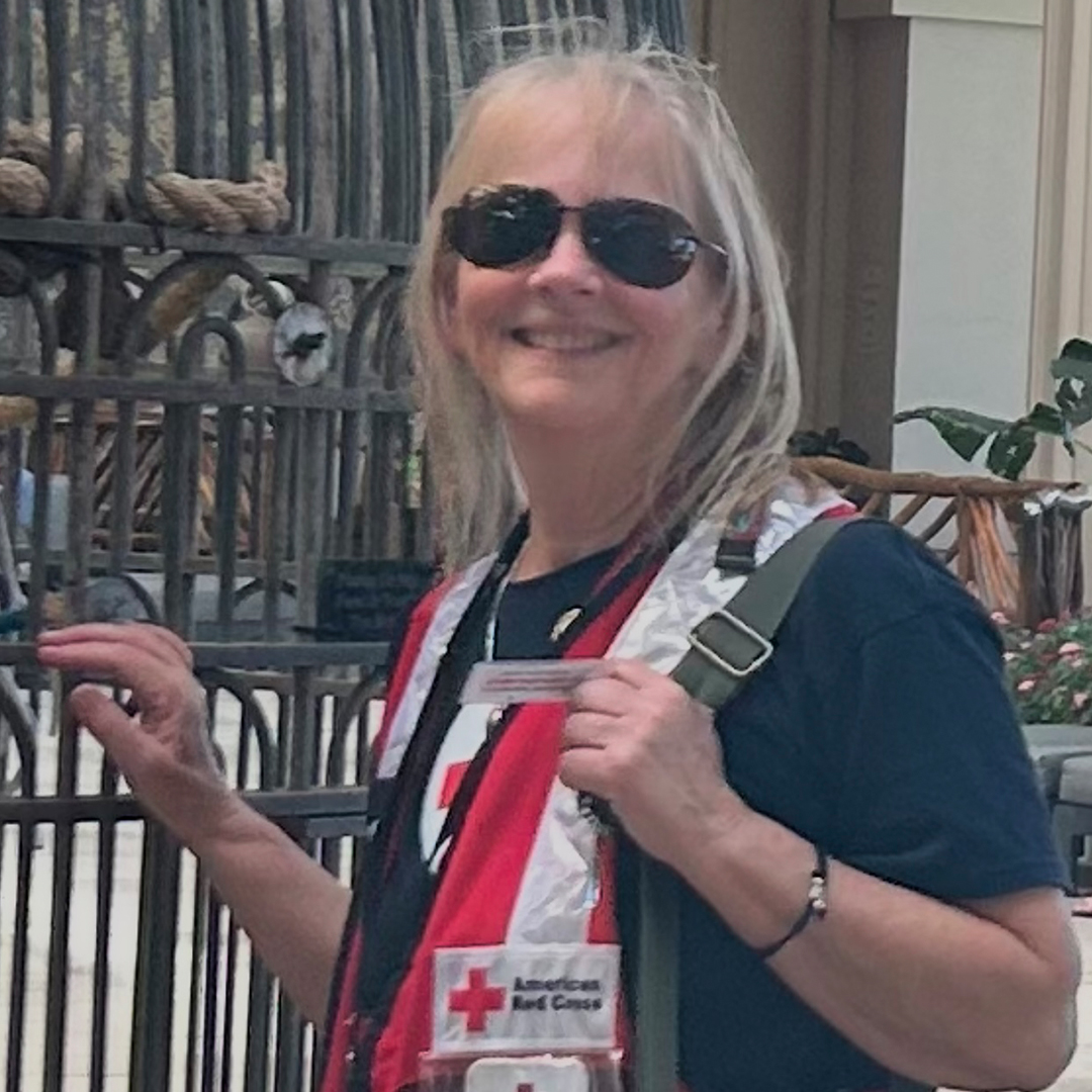 Red Cross volunteer Kate Byrnes wearing a Red Cross disaster vest over a black T-shirt and sunglasses.
