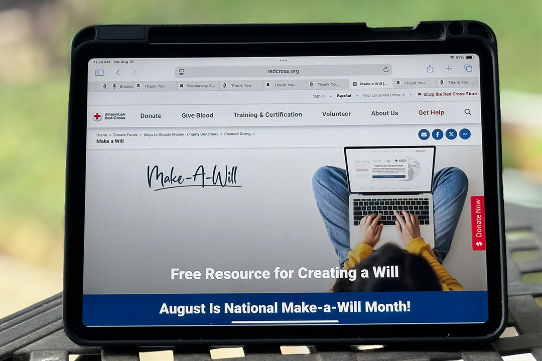 Photo of an iPad propped up on a table outside showing the Red Cross webpage with resources to create a will. 