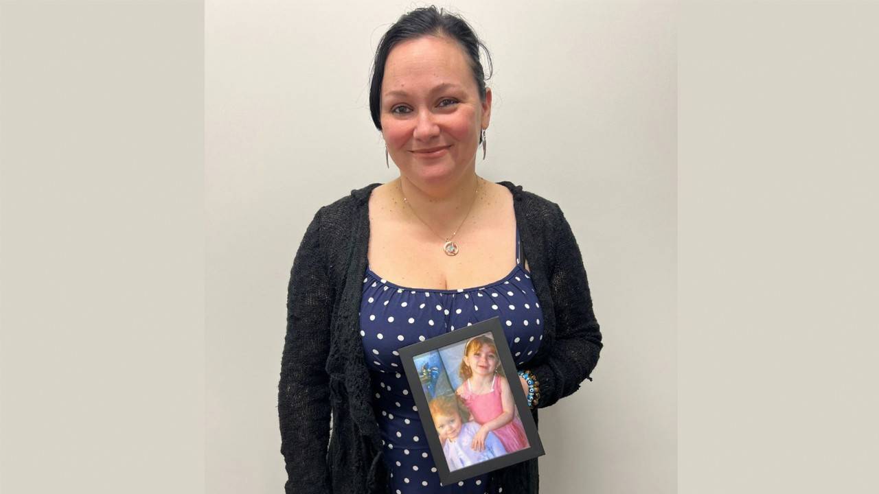 Nora Magras is shown holding a framed picture of her two daughters, Felisha and Hailey, taken at Easter in 2008 shortly before the fire.