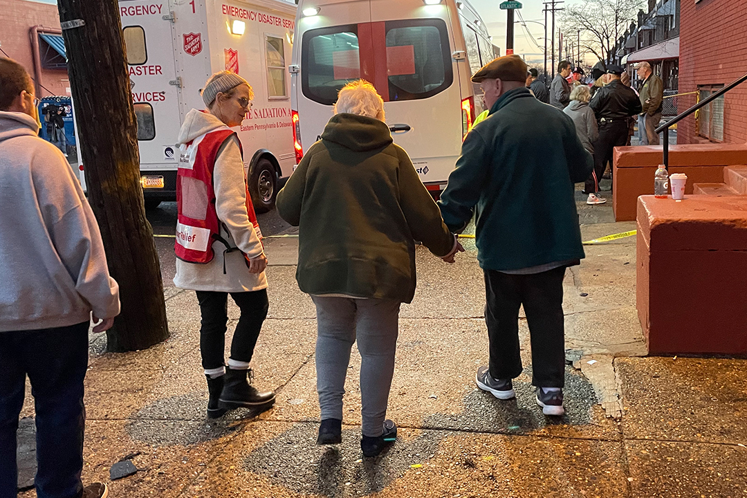 Photo of Red Cross volunteer Randy Miller guiding an elderly couple to an Emergency Response Vehicle following a disaster.