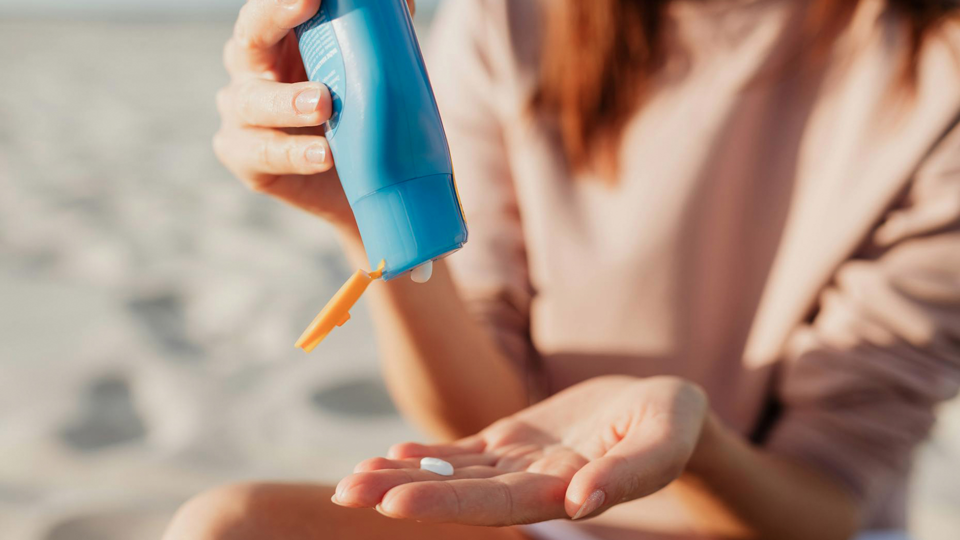 Photo of a woman sqeezing sunscrren from a tube  into her palm