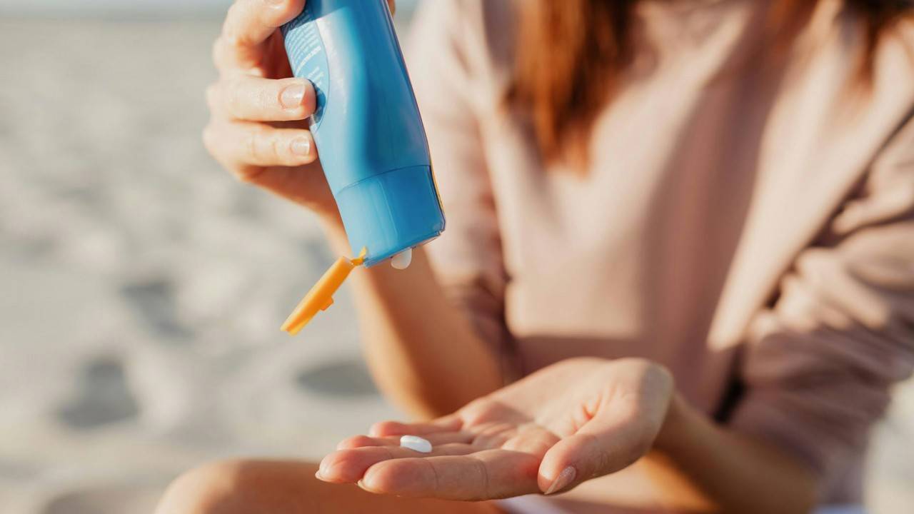 Photo of a woman squeezing sunscreen from a tube into her palm