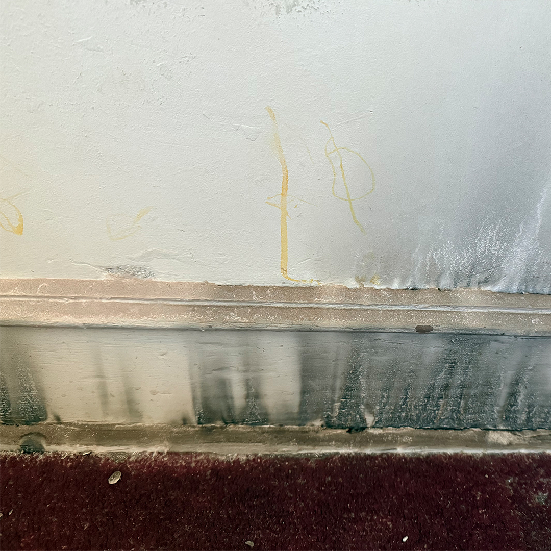 Heavy dark soot and smoke staining covering a light-colored wall and baseboard.