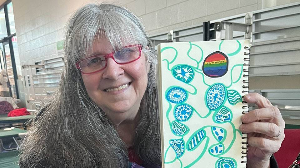 Ellie Kane holding up a sketch she made on notebook paper.