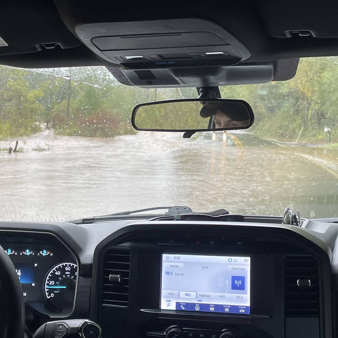 Dashboard view of a person driving a car in a flood