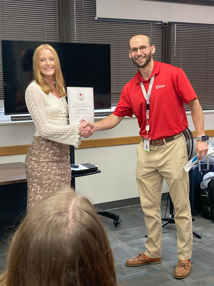 Katelyn Williams receives Red Cross award from Red Cross employee.