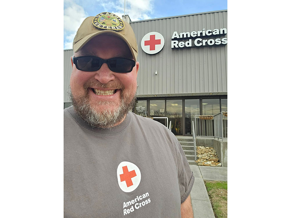 Joseph Hall takes a selfie in front of a Red Cross building.