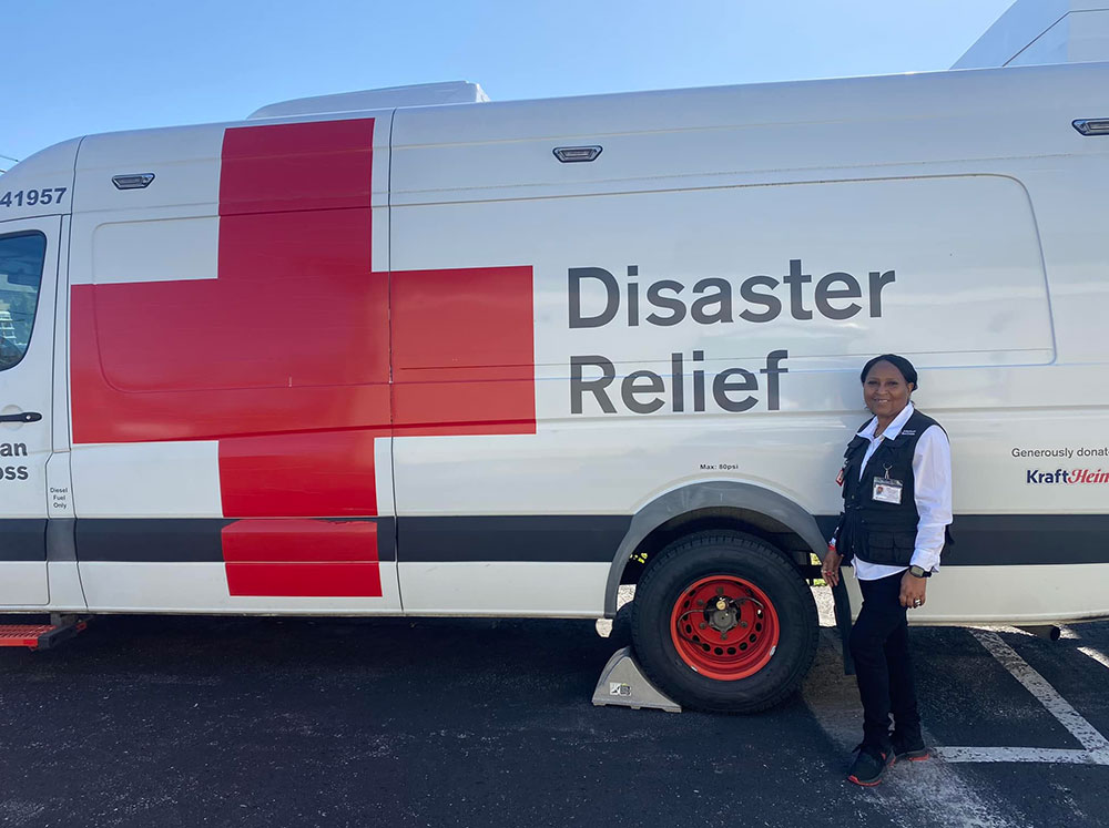Red Cross volunteer Mary Lockett standing next to a Red Cross van.