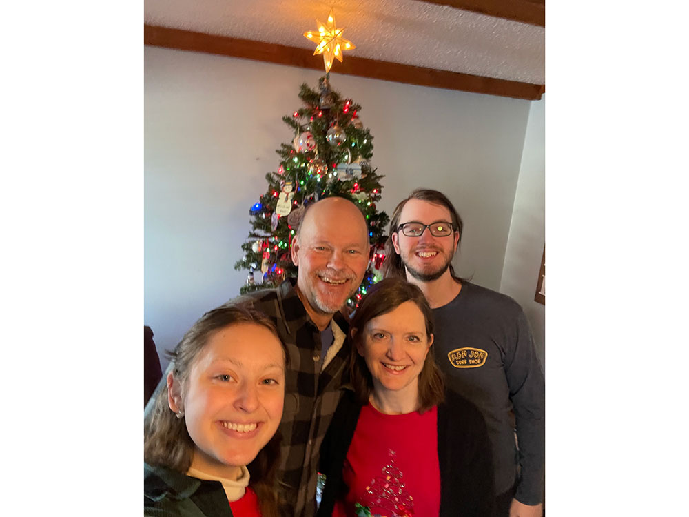 Pete Hinerman, his wife and two young adults take a selfie with christmas tree in the background.