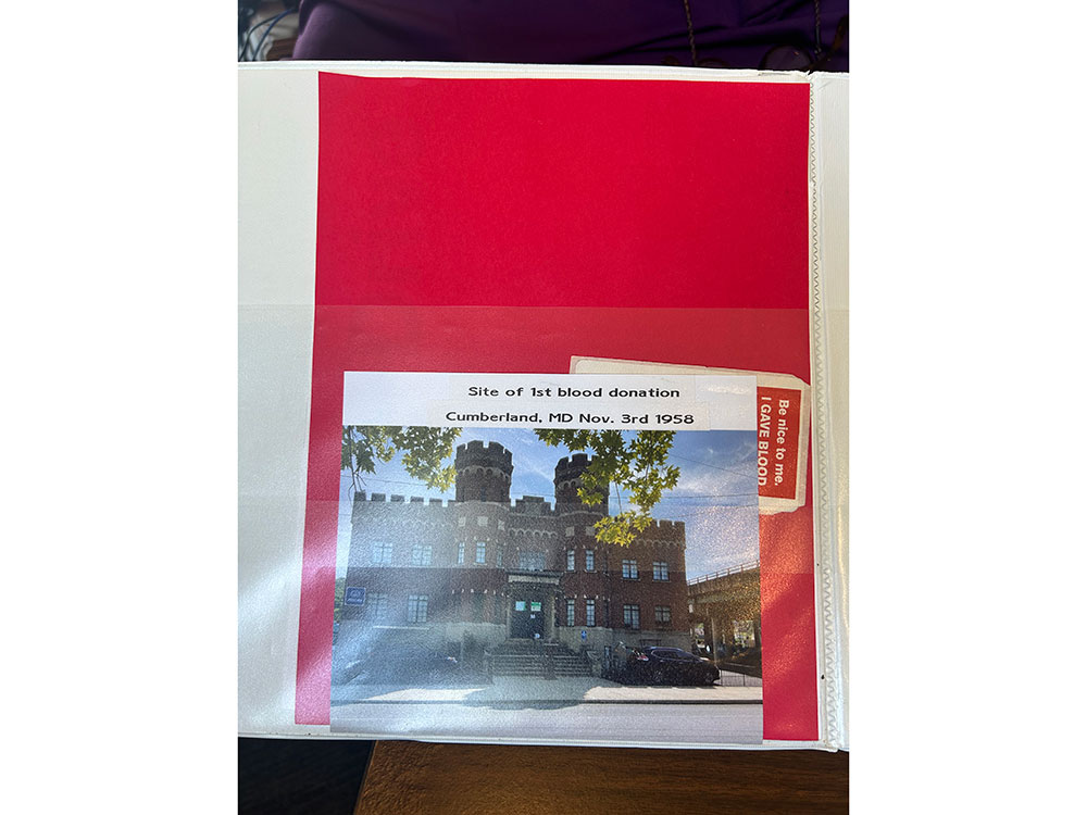 A photo of a historic castle-like building labeled "Site of 1st blood donation, Cumberland, MD Nov. 3rd, 1958," in a red and white display folder.