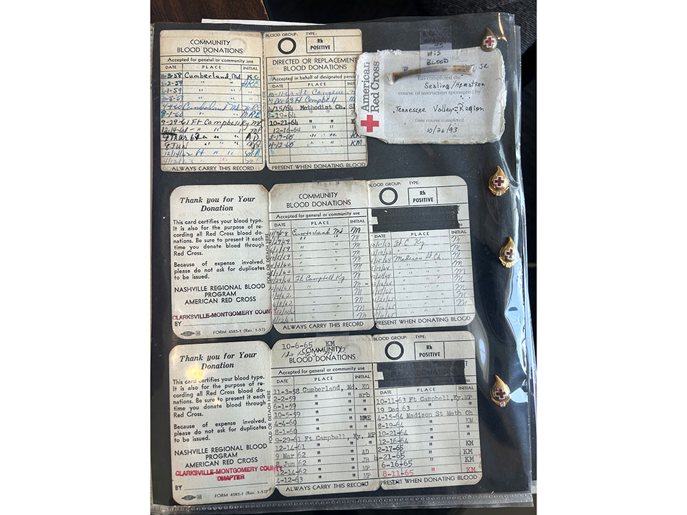 Ray Swadley's collection of vintage blood donation cards showing multiple entries from various dates and locations. The cards are labeled "Community Blood Donations" by the American Red Cross, with blood type "O Positive" noted. The background includes Red Cross insignias on the right.