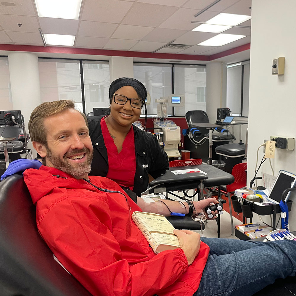 Ryan Meyer donates blood at the Nashville Red Cross Blood, Platelet and Plasma Donation Center, with a nurse next to him.