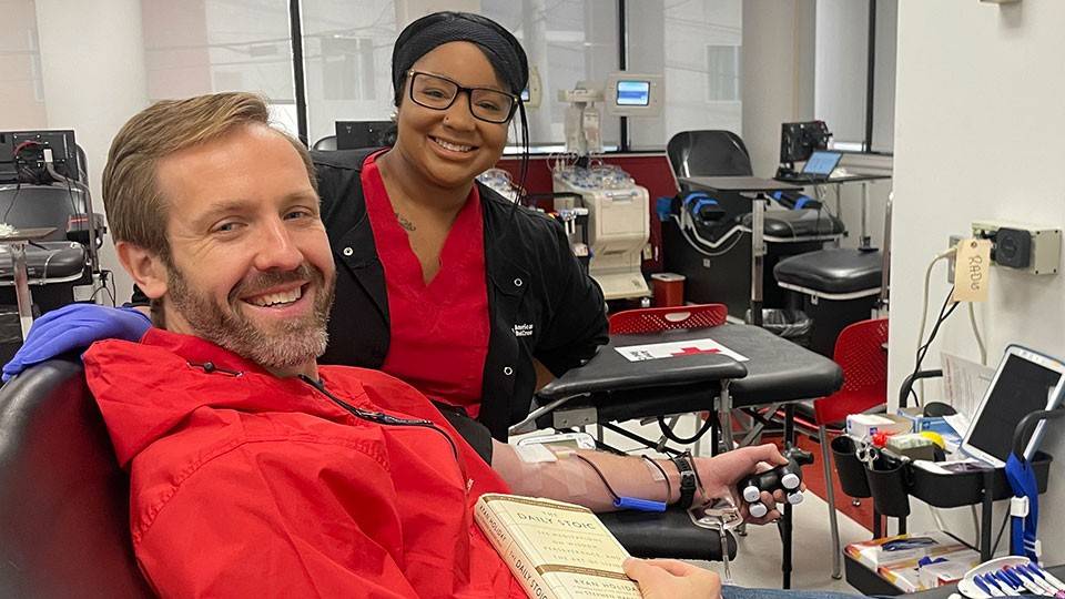 Ryan Meyer donates blood at the Nashville Red Cross Blood, Platelet and Plasma Donation Center, with a nurse next to him.