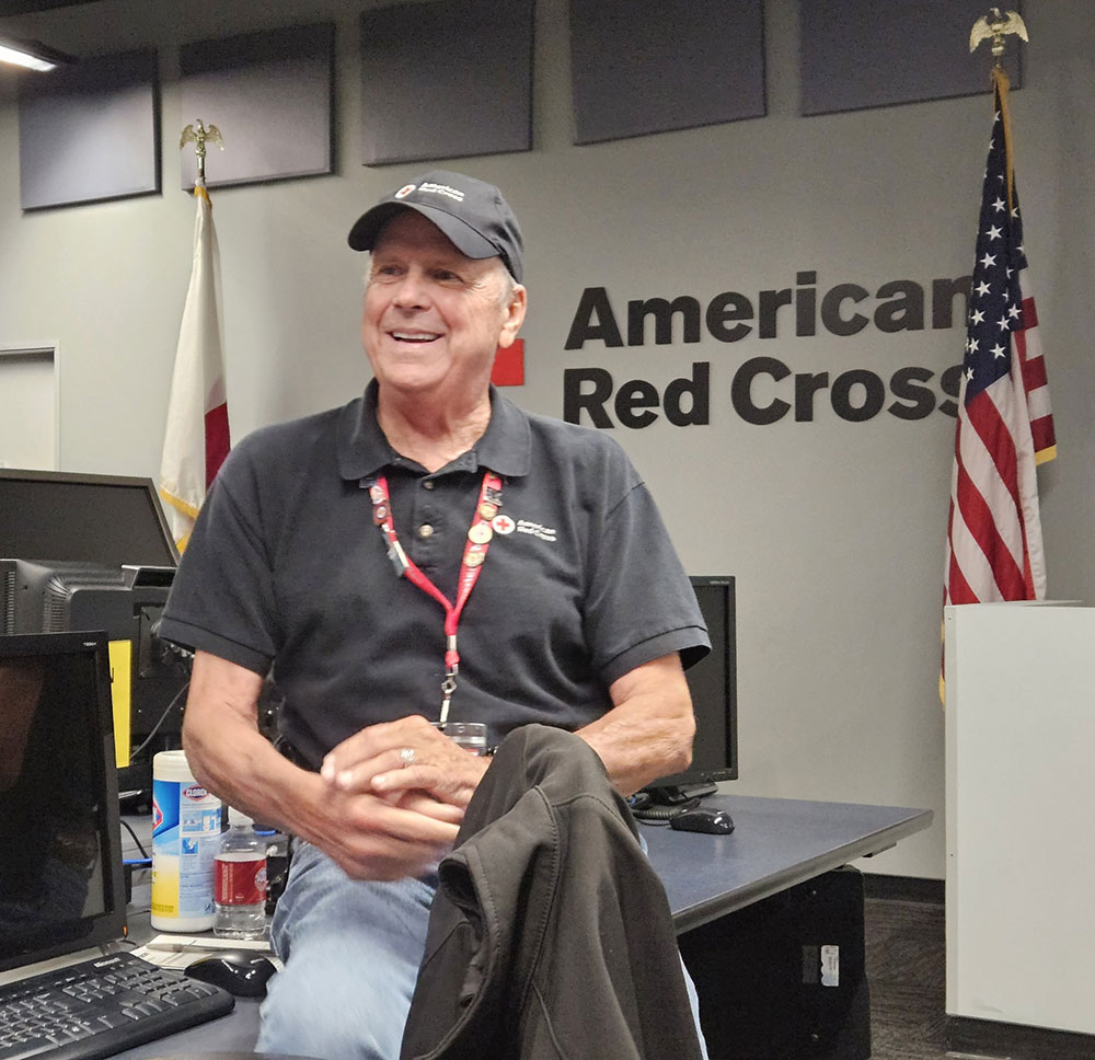 Tom Fortney inside American Red Cross building wearing an American Red Cross hat, shirt and lanyard.