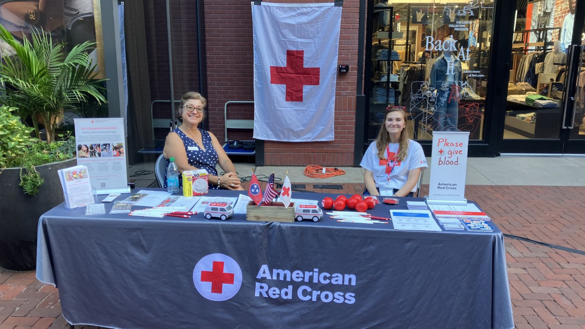 two volunteers at red cross information table outside