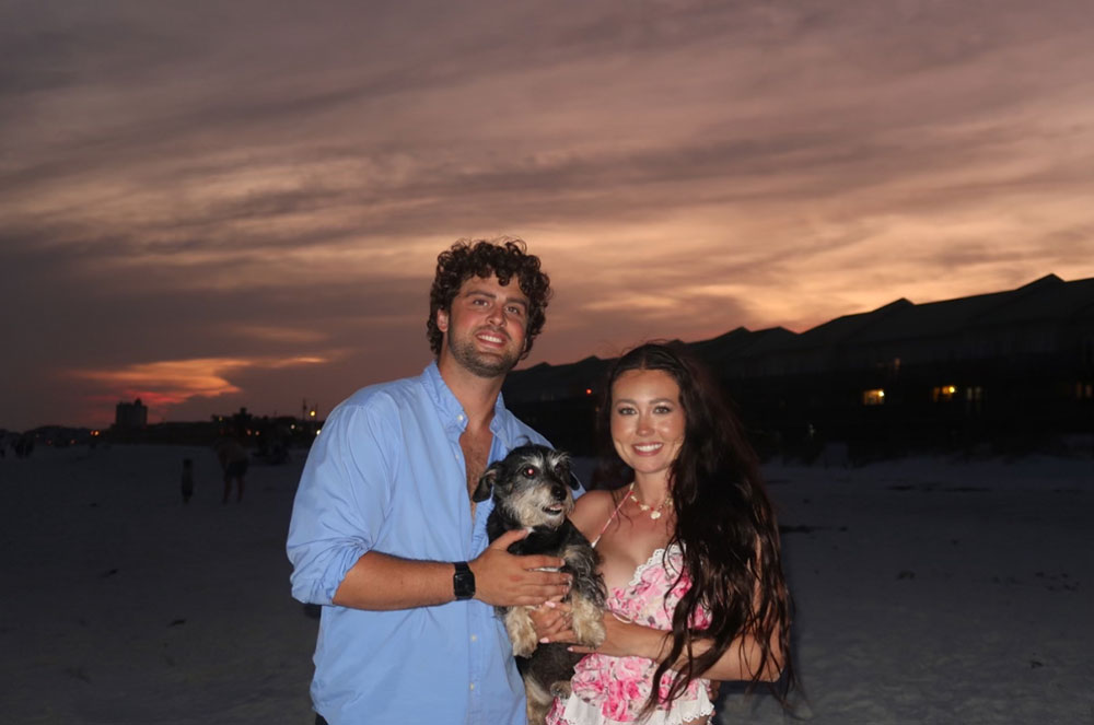 Hannah Jones and her husband Kenny Minasian holding their dog, Toby, on the beach at night.