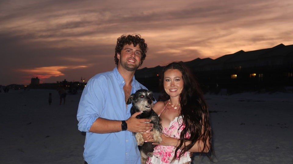 Hannah Jones and her husband Kenny Minasian holding their dog, Toby, on the beach at night.