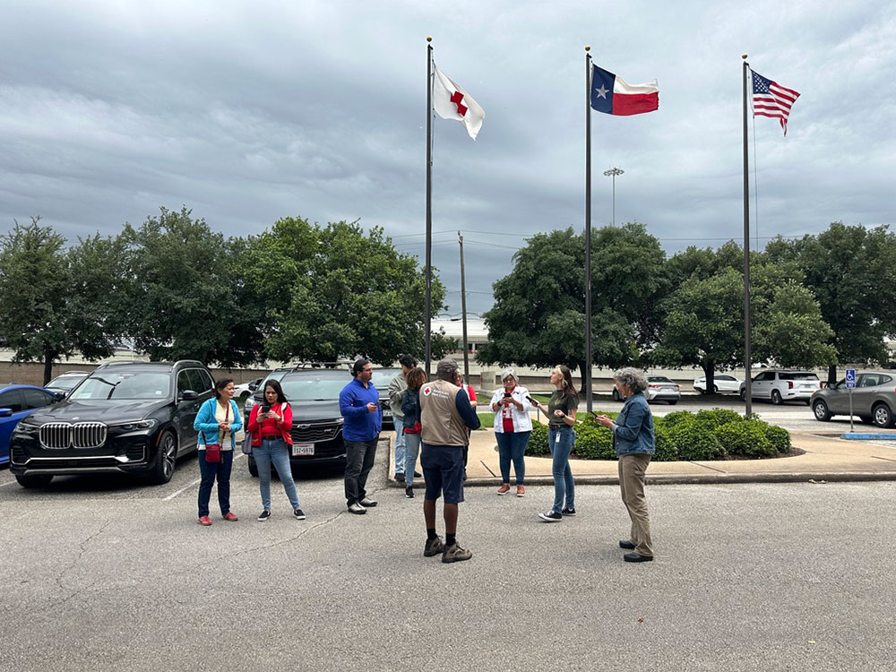 Red Cross volunteers waiting in parking lot next to flag poles