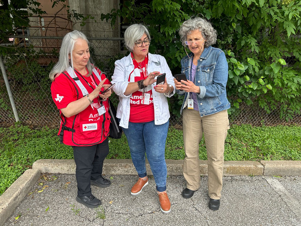 Red Cross volunteers in parking lot looking at cell phones
