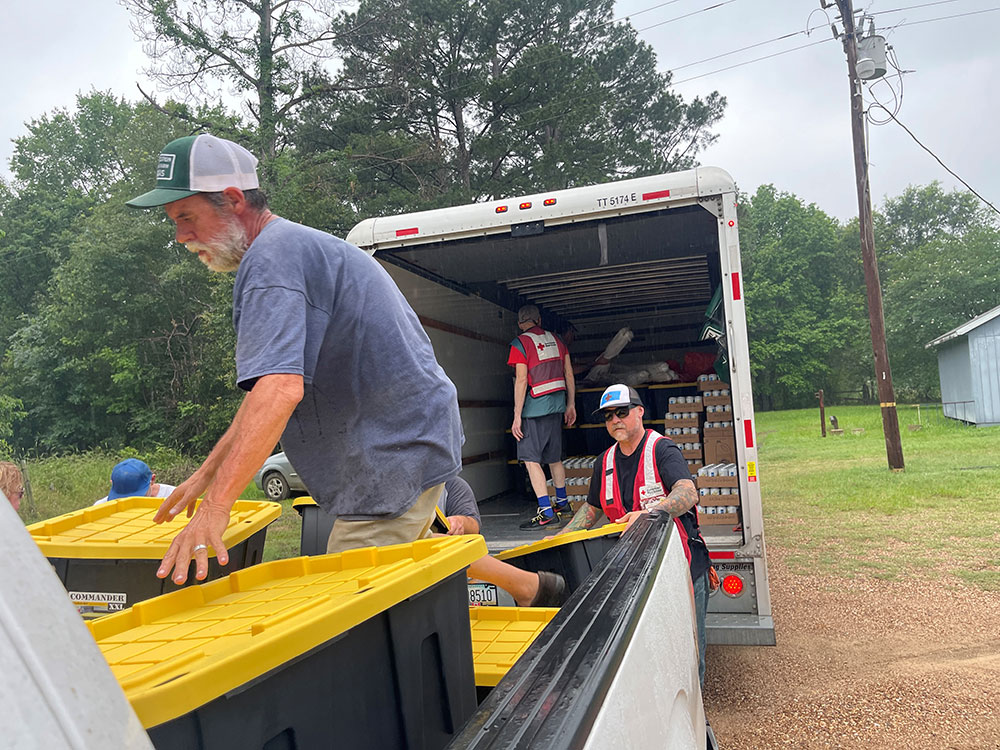 Red Cross volunteers loading containers and drinks from one truck to another