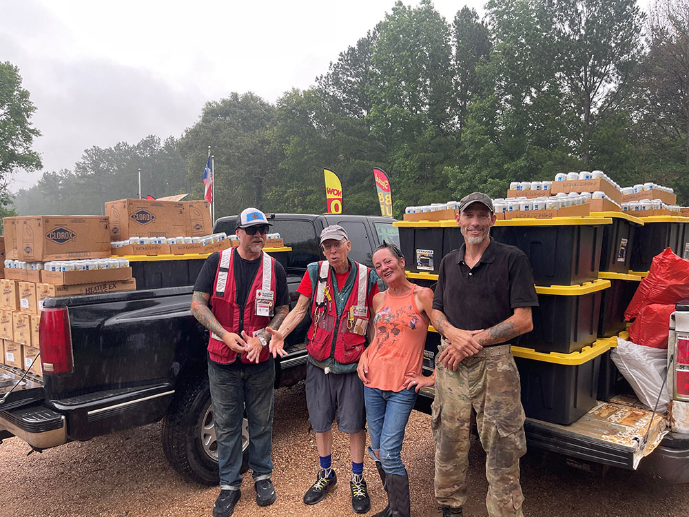 Red Cross volunteers smiling and standing in front of loaded trucks 