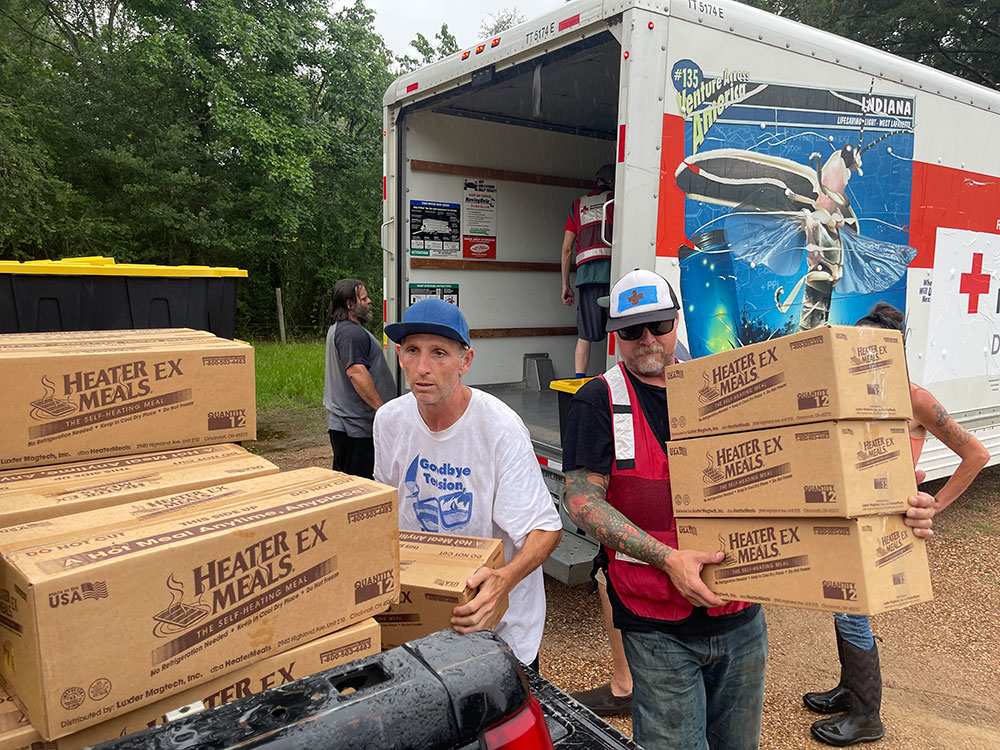 Red Cross volunteers loading boxes of food from one truck to another