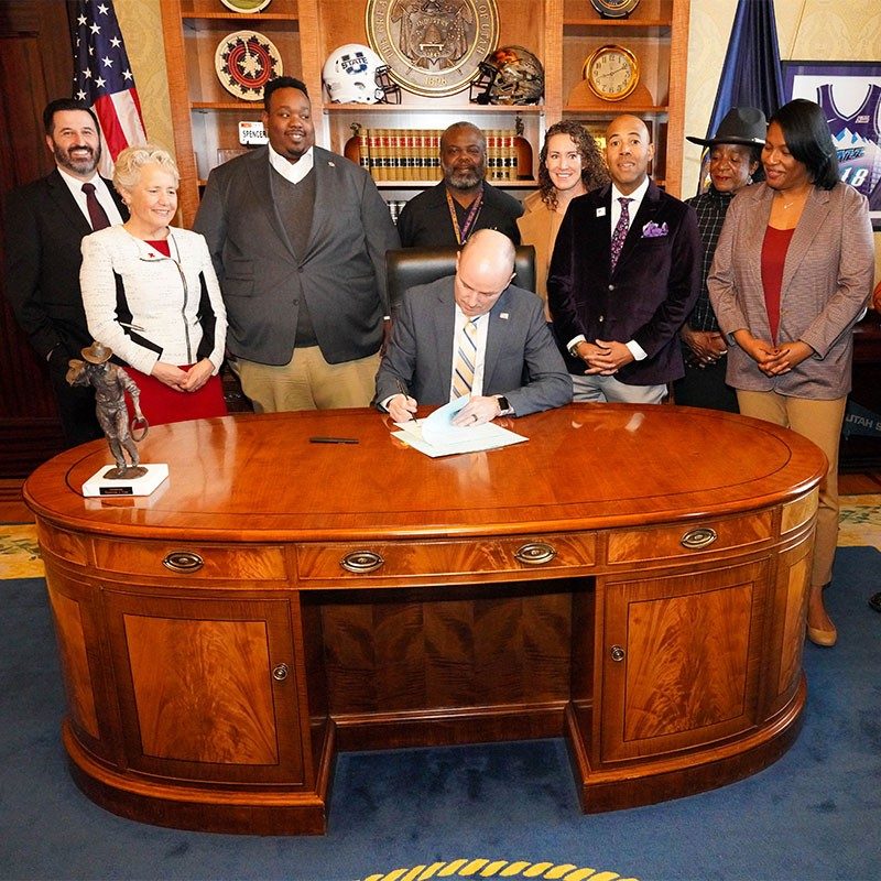 Gov. Spencer Cox signing bill with group of people.