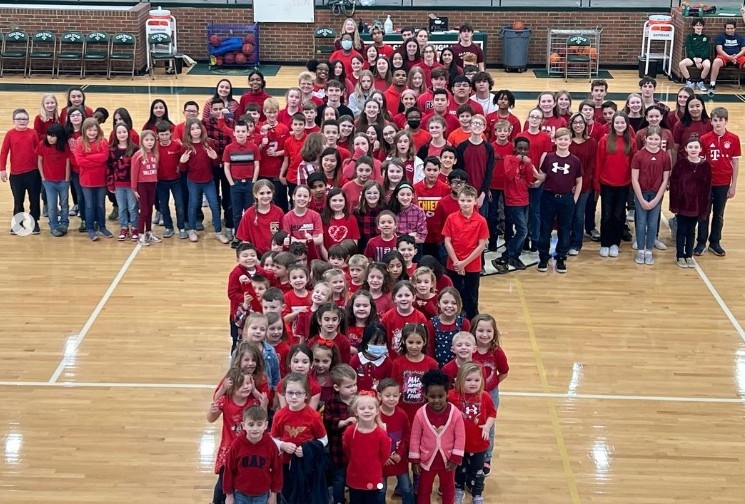 Group of students in red shirts standing in formation of the Red Cross logo