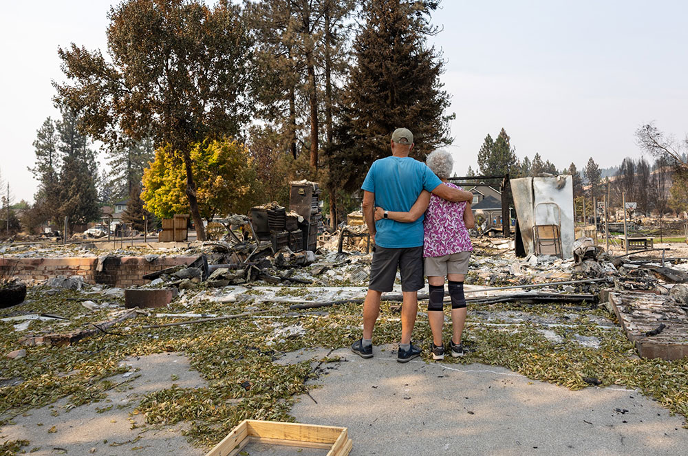 Doug and Georgann Howie, with one arm around each other, while looking at the remains of their burned home.