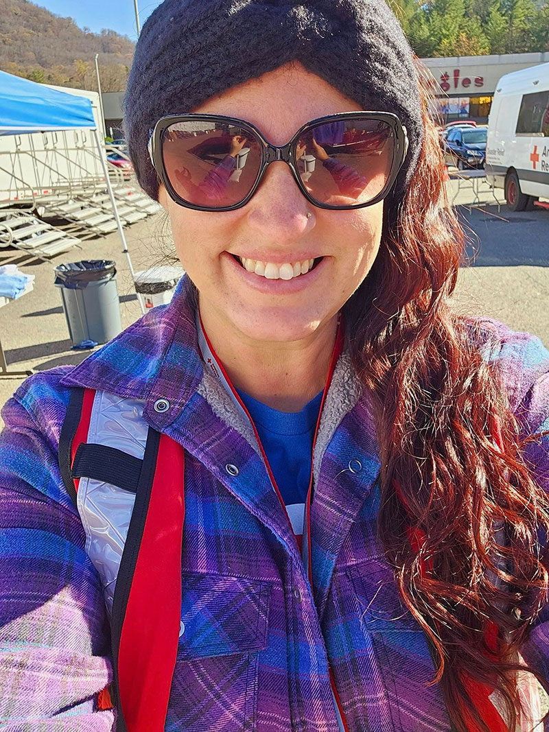 Rachel Rosenbaum wearing headband, sun glasses and Red Cross vest and taking a selfie.